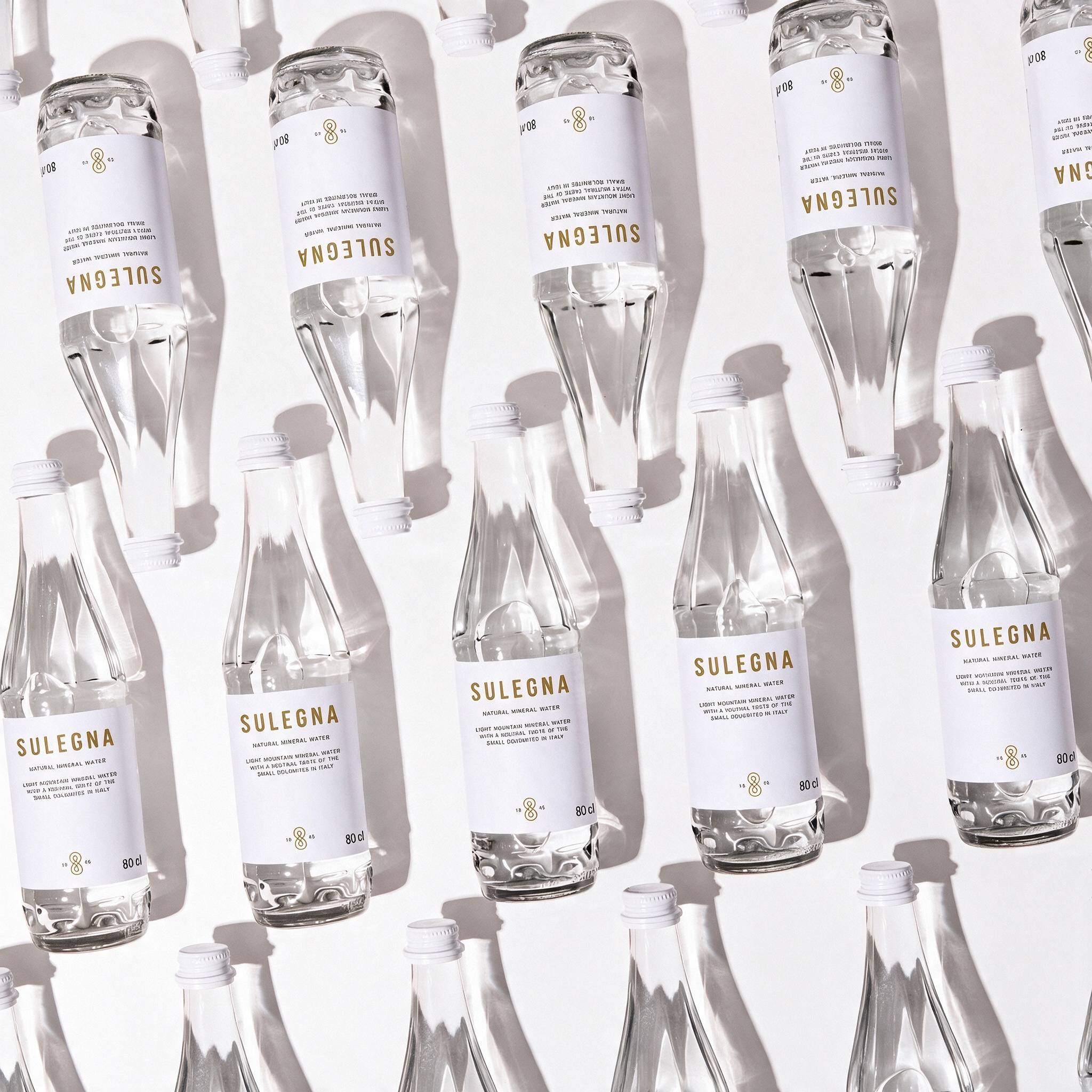 SULEGNA Natural bottles, 80 cl and 44 cl, standing together on a warm neutral background